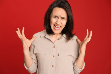 Photo of Portrait of screaming woman filled with hate on red background