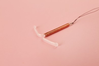 Photo of Copper intrauterine contraceptive device on light pink background