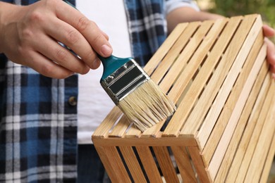 Photo of Man applying varnish onto wooden crate, closeup