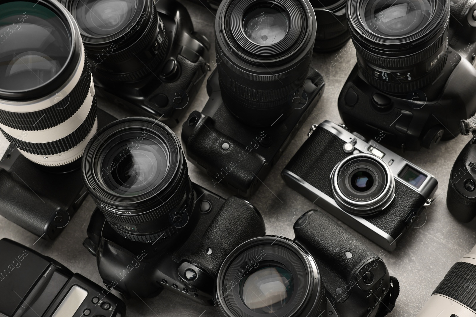 Photo of Modern cameras on gray table, closeup. Professional photography equipment