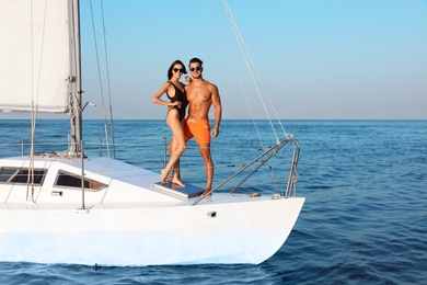 Photo of Young man and his beautiful girlfriend in bikini on yacht. Happy couple during sea trip