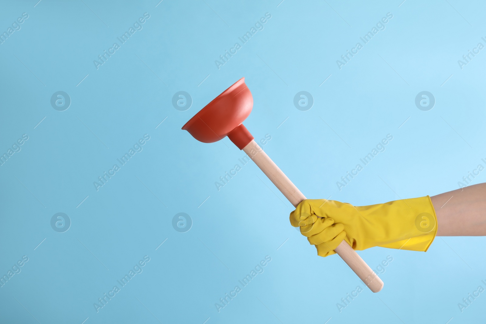 Photo of Woman holding plunger on turquoise background, closeup. Space for text