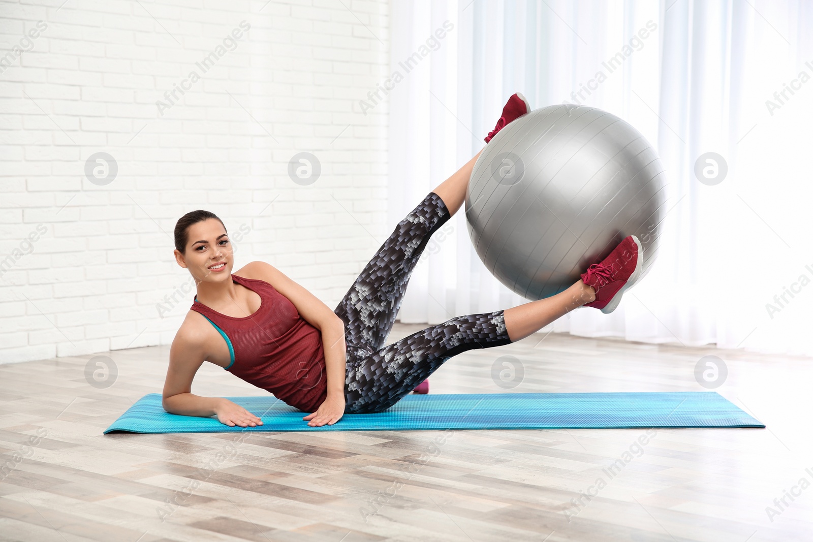 Photo of Young beautiful woman with ball doing exercise at home. Workout and fitness