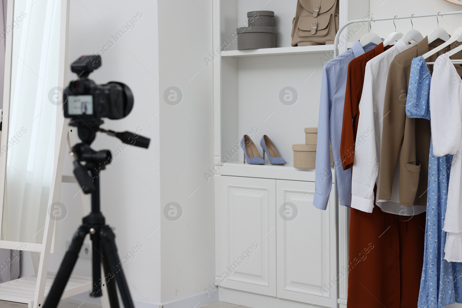 Photo of Fashion blogger's workplace. Shoes, clothes, camera and stylish furniture indoors