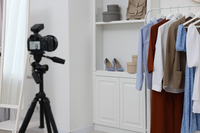 Fashion blogger's workplace. Shoes, clothes, camera and stylish furniture indoors