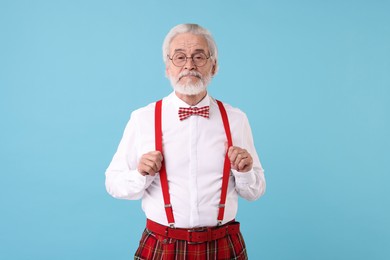 Photo of Portrait of stylish grandpa with glasses and bowtie on light blue background