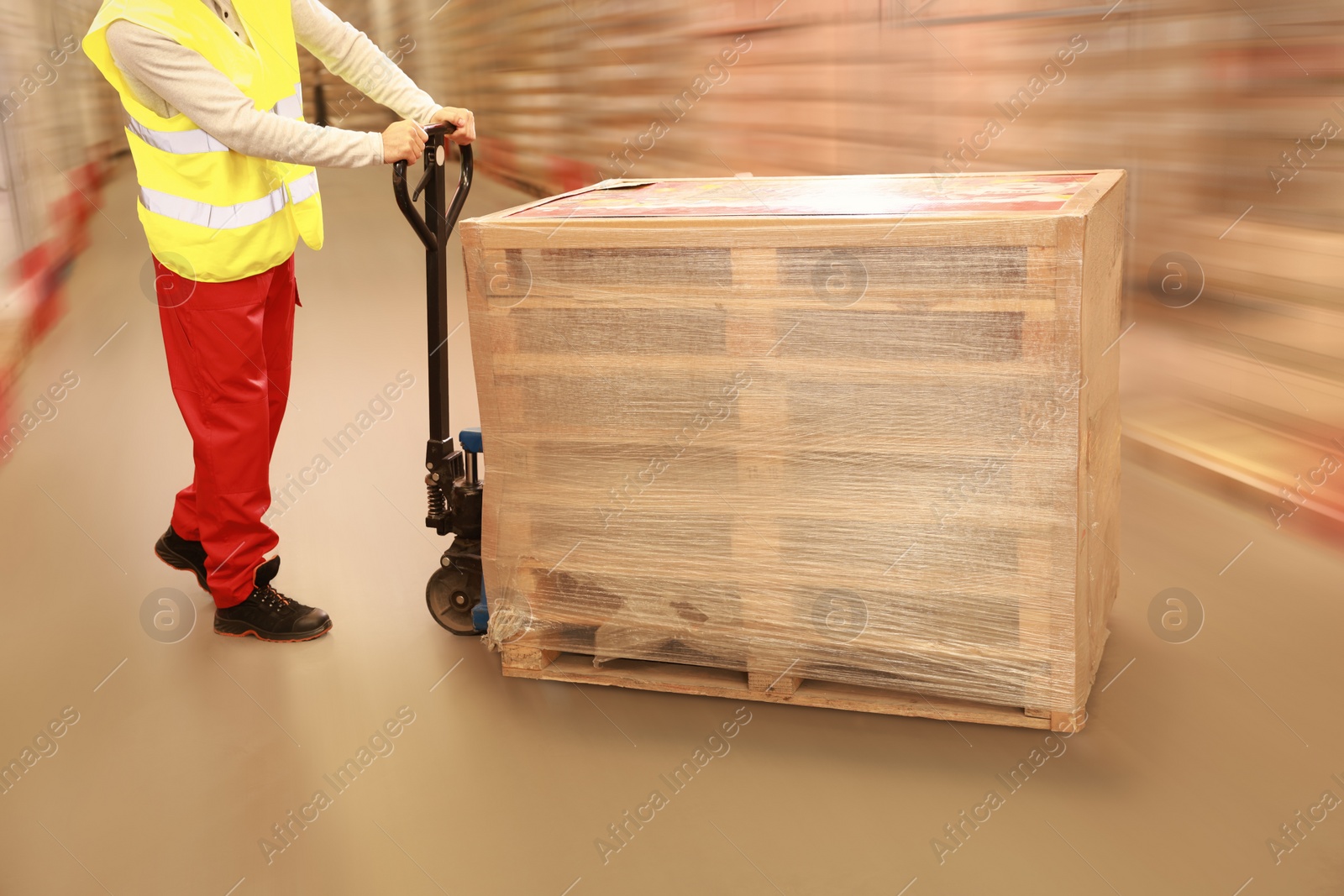 Image of Worker moving wrapped wooden pallets with manual forklift in warehouse, closeup