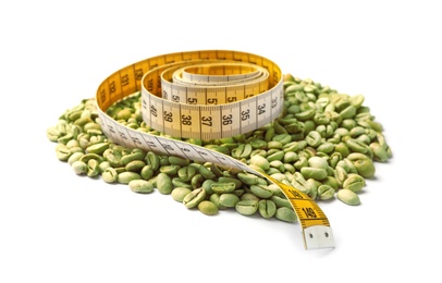 Photo of Pile of green coffee beans and measuring tape on white background