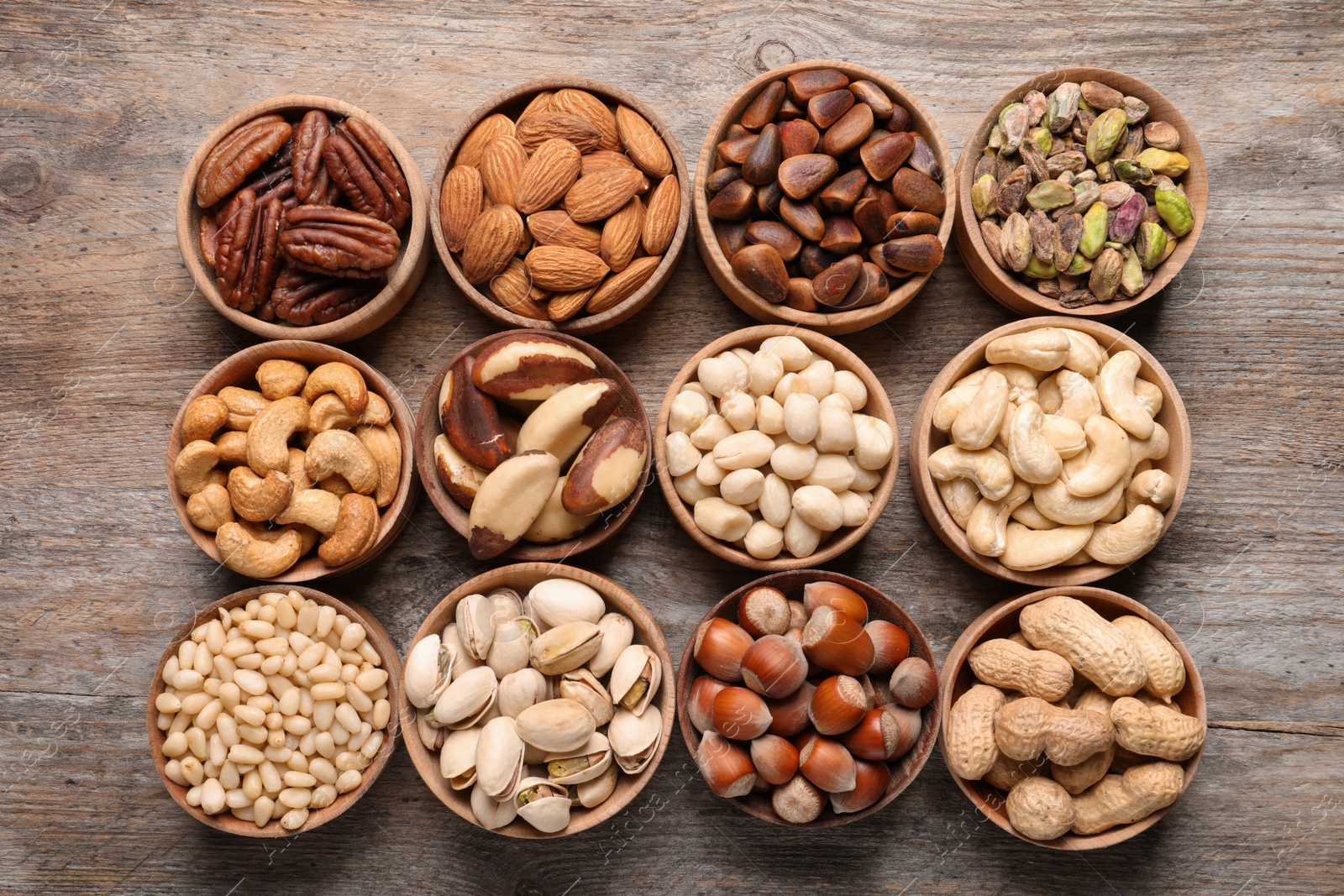 Photo of Flat lay composition with organic nuts on wooden background, top view. Snack mix