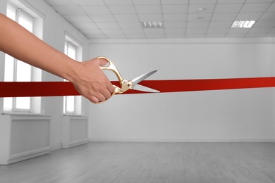 Photo of Woman cutting red ribbon on blurred background. Festive ceremony