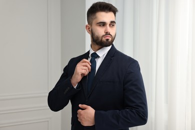 Handsome businessman in suit and necktie indoors