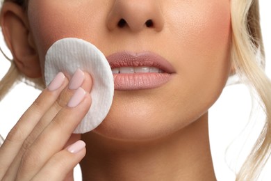 Photo of Woman removing makeup with cotton pad on white background, closeup