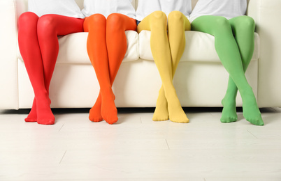 Women wearing colorful tights sitting on sofa indoors, closeup