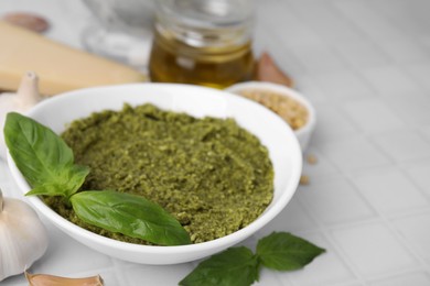 Photo of Bowl with tasty pesto sauce and fresh basil on white table, closeup. Space for text