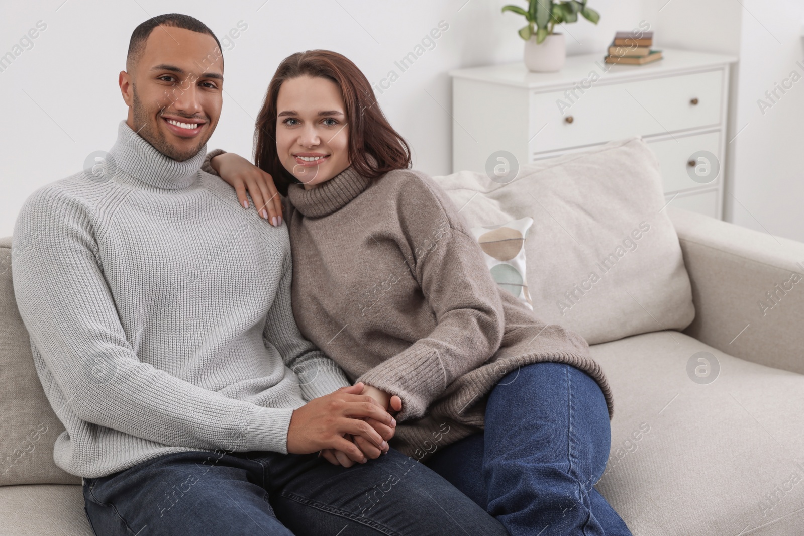 Photo of Dating agency. Happy couple holding hands on sofa at home