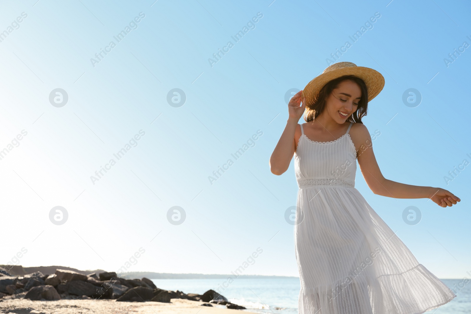 Photo of Happy young woman with hat on beach near sea. Space for text