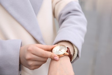 Woman with luxury wristwatch on blurred background, closeup