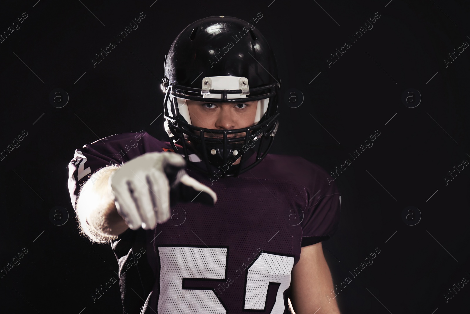 Photo of American football player wearing uniform on dark background