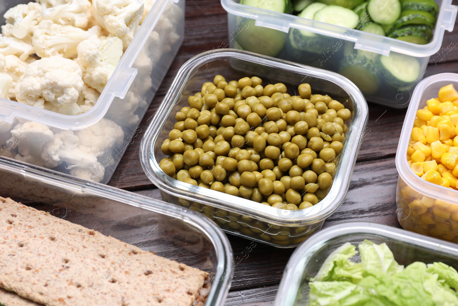 Photo of Plastic and glass containers with different fresh products on wooden table, closeup