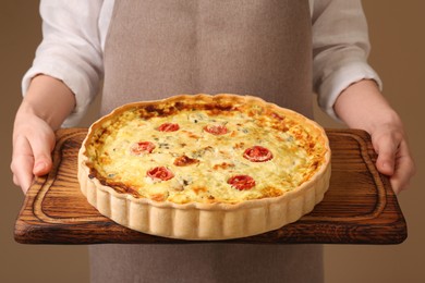 Photo of Woman with delicious homemade cheese quiche on beige background, closeup