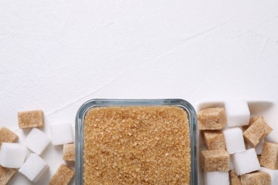 Photo of Different sugar cubes in bowls on white table, flat lay. Space for text