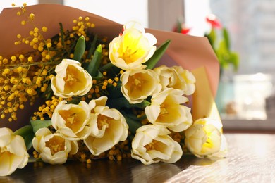 Photo of Bouquet with beautiful tulips and mimosa flowers on wooden table indoors