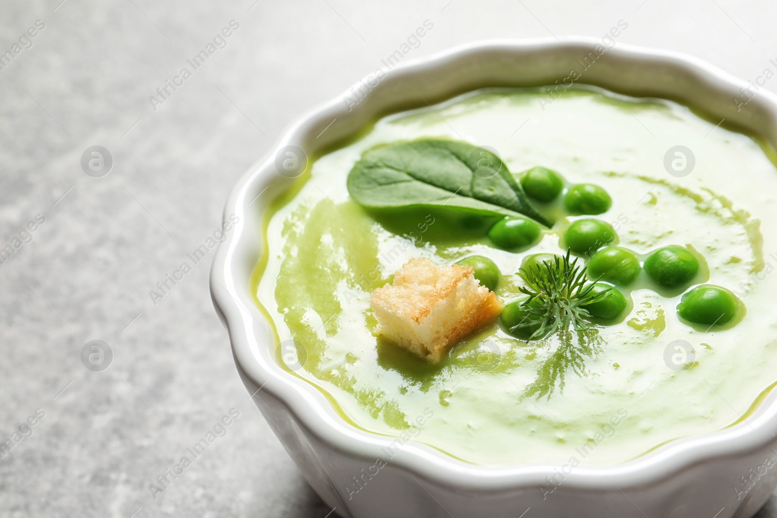 Photo of Fresh vegetable detox soup made of green peas and spinach in dish on table, closeup