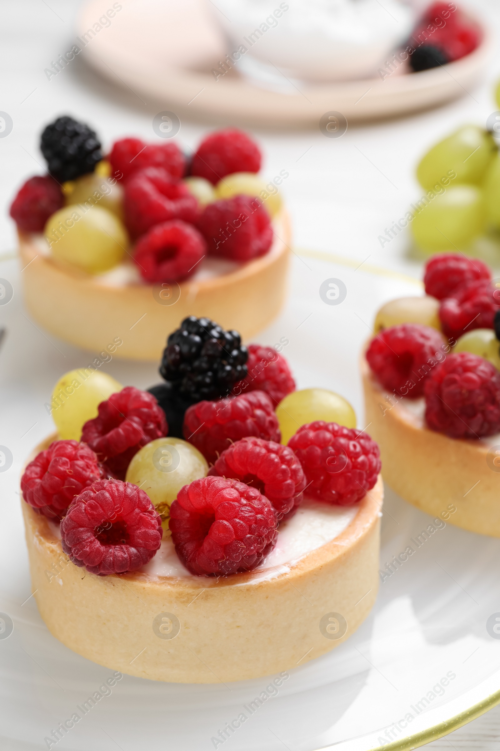 Photo of Delicious tartlets with berries on plate, closeup