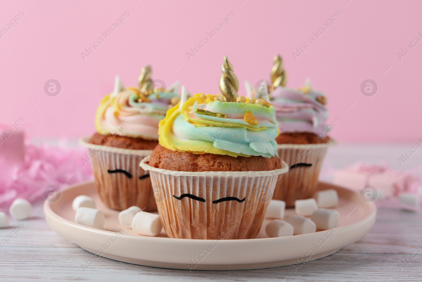 Photo of Cute sweet unicorn cupcakes on white wooden table