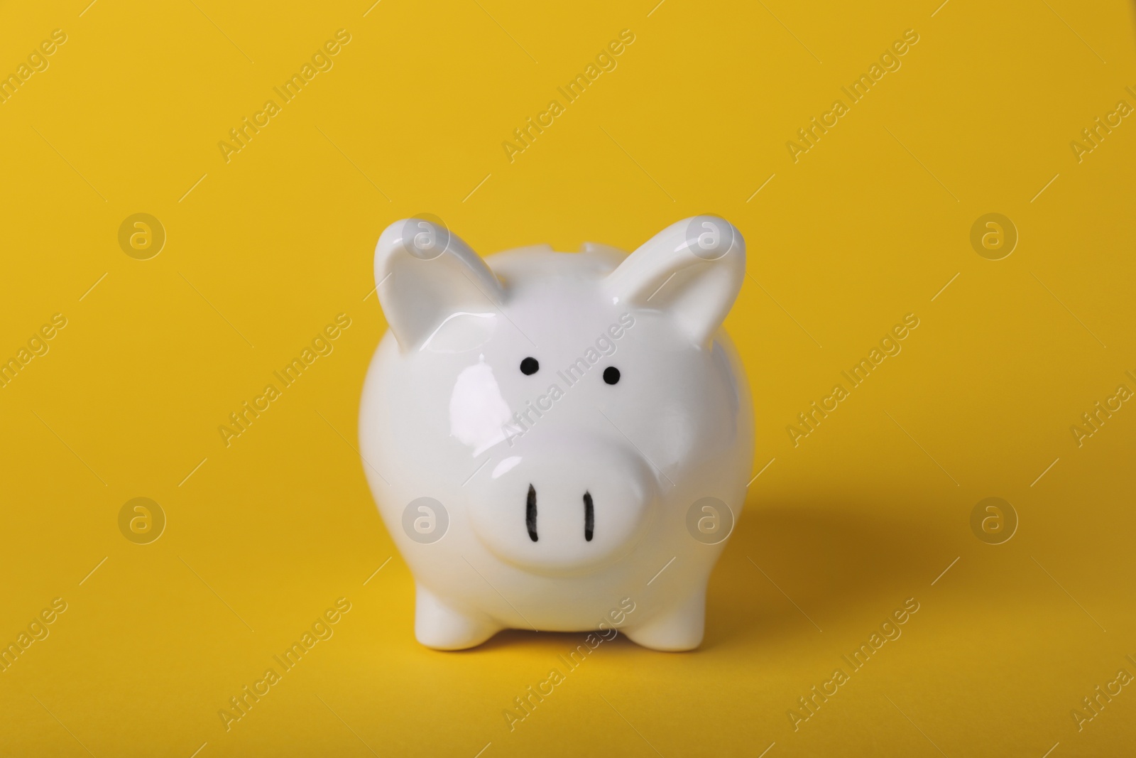 Photo of Ceramic piggy bank on yellow background. Financial savings