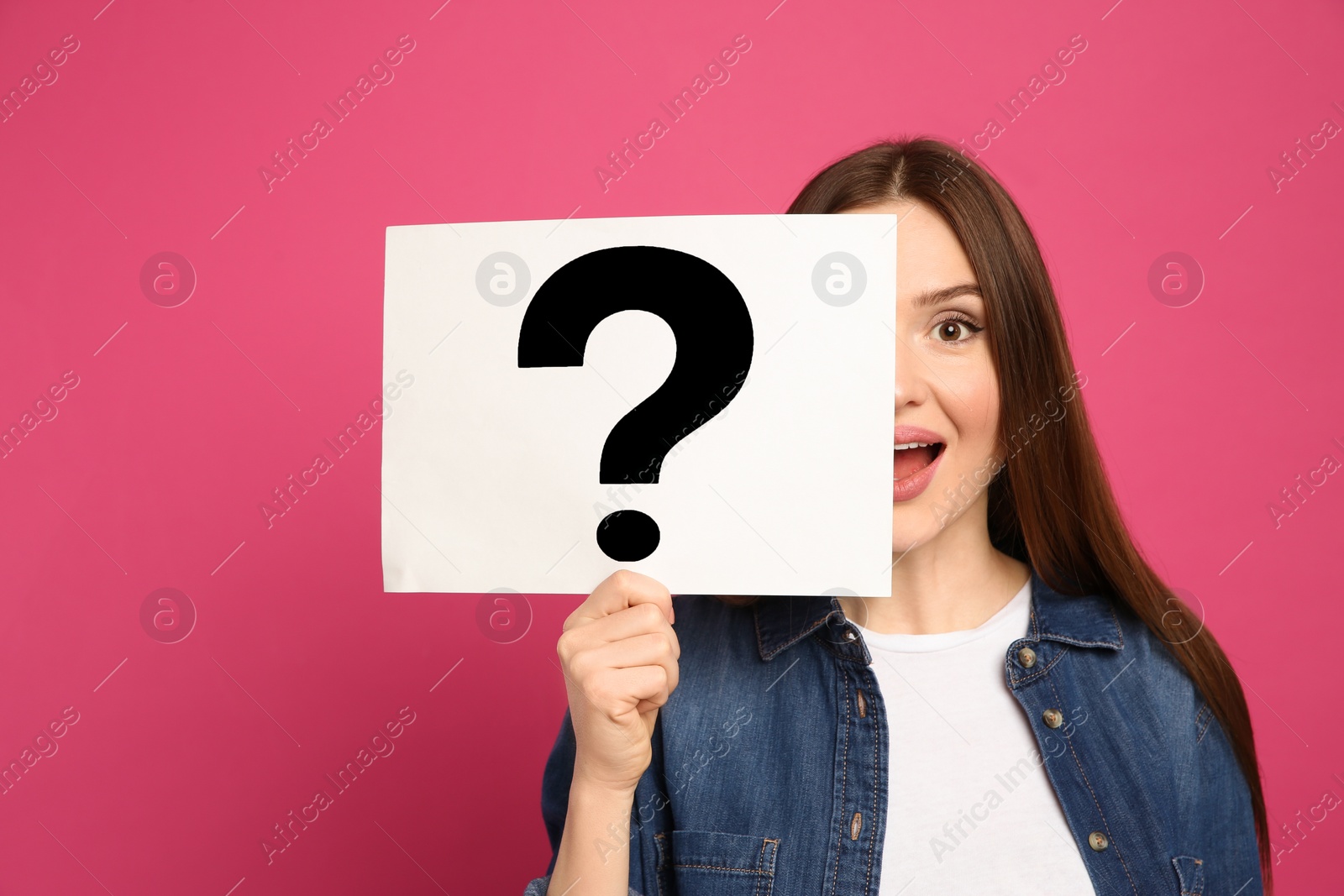 Photo of Emotional woman holding question mark sign on pink background