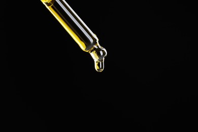 Photo of Dripping tincture from pipette on black background, closeup. Space for text