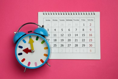 Photo of Alarm clock and calendar on pink background, flat lay. Reminder concept