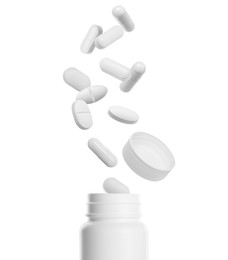 Many different pills falling into bottle on white background