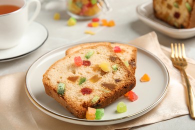 Delicious cake with candied fruits and tea on light table