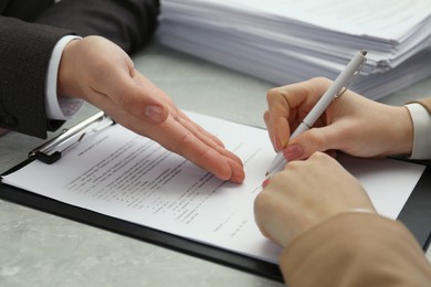 Woman signing document at table in office, closeup