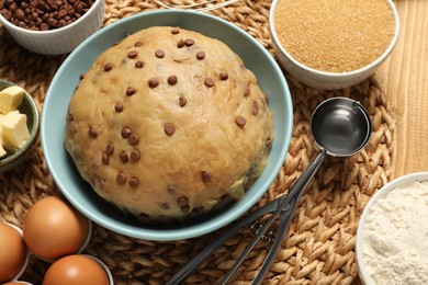 Photo of Fresh dough and ingredients for cooking chocolate chip cookies on wooden table, above view