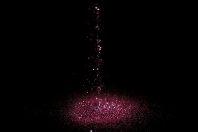 Photo of Sprinkling rose glitter on black background, bokeh effect