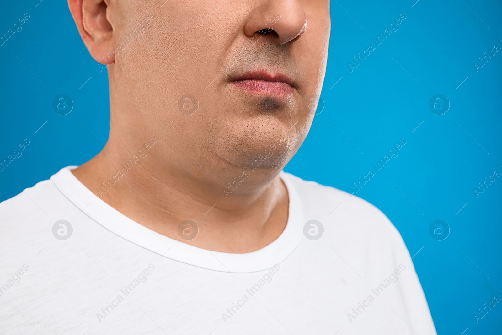 Photo of Mature man with double chin on blue background, closeup