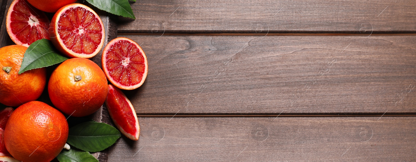 Image of Ripe sicilian oranges with green leaves on wooden table, top view with space for text. Banner design