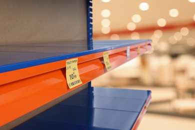 Image of Empty shelves in supermarket, closeup. Product deficiency due to social panic 