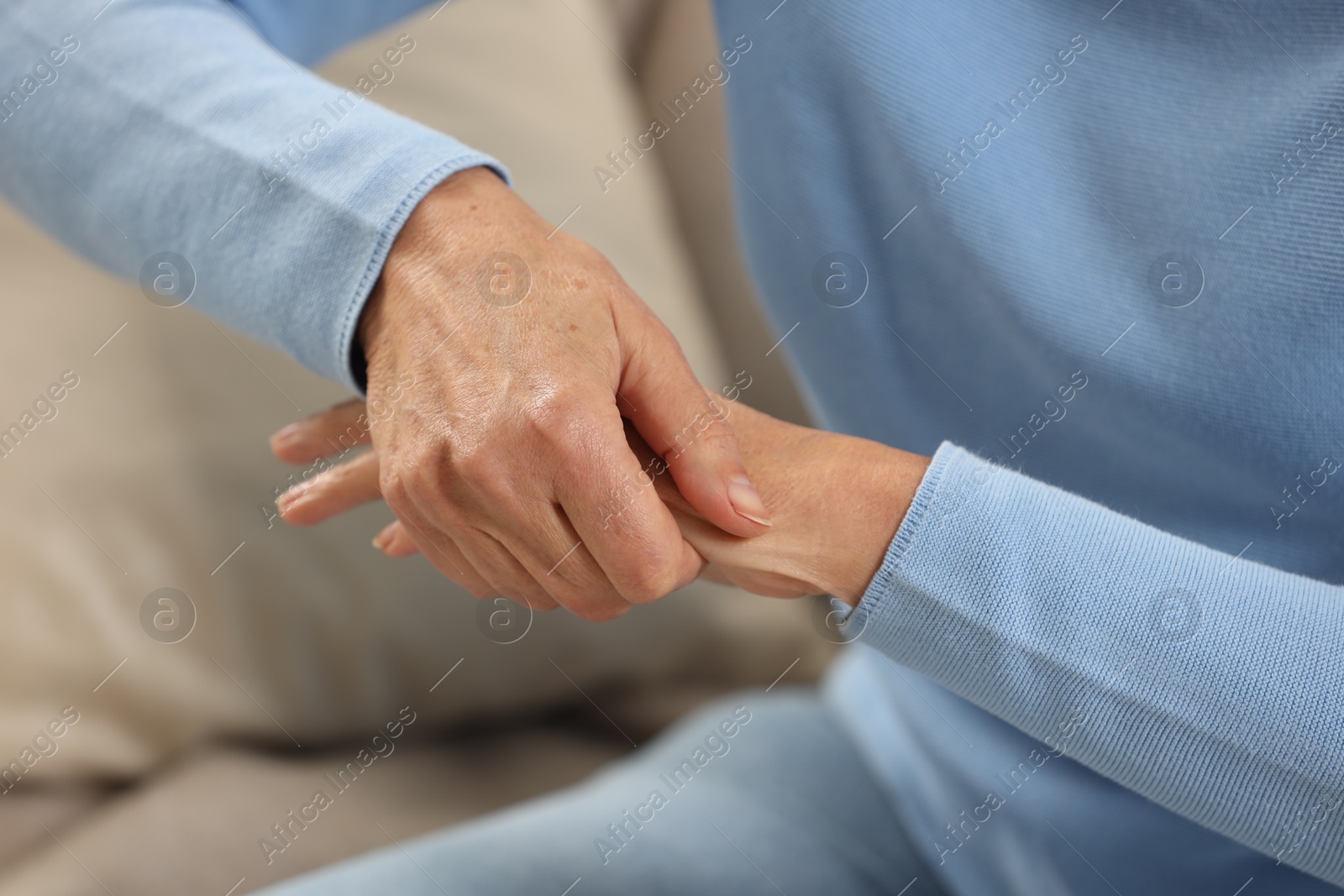 Photo of Mature woman suffering from pain in hand on sofa, closeup. Rheumatism symptom