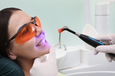 Professional dentist working with patient in modern clinic, closeup. Teeth whitening