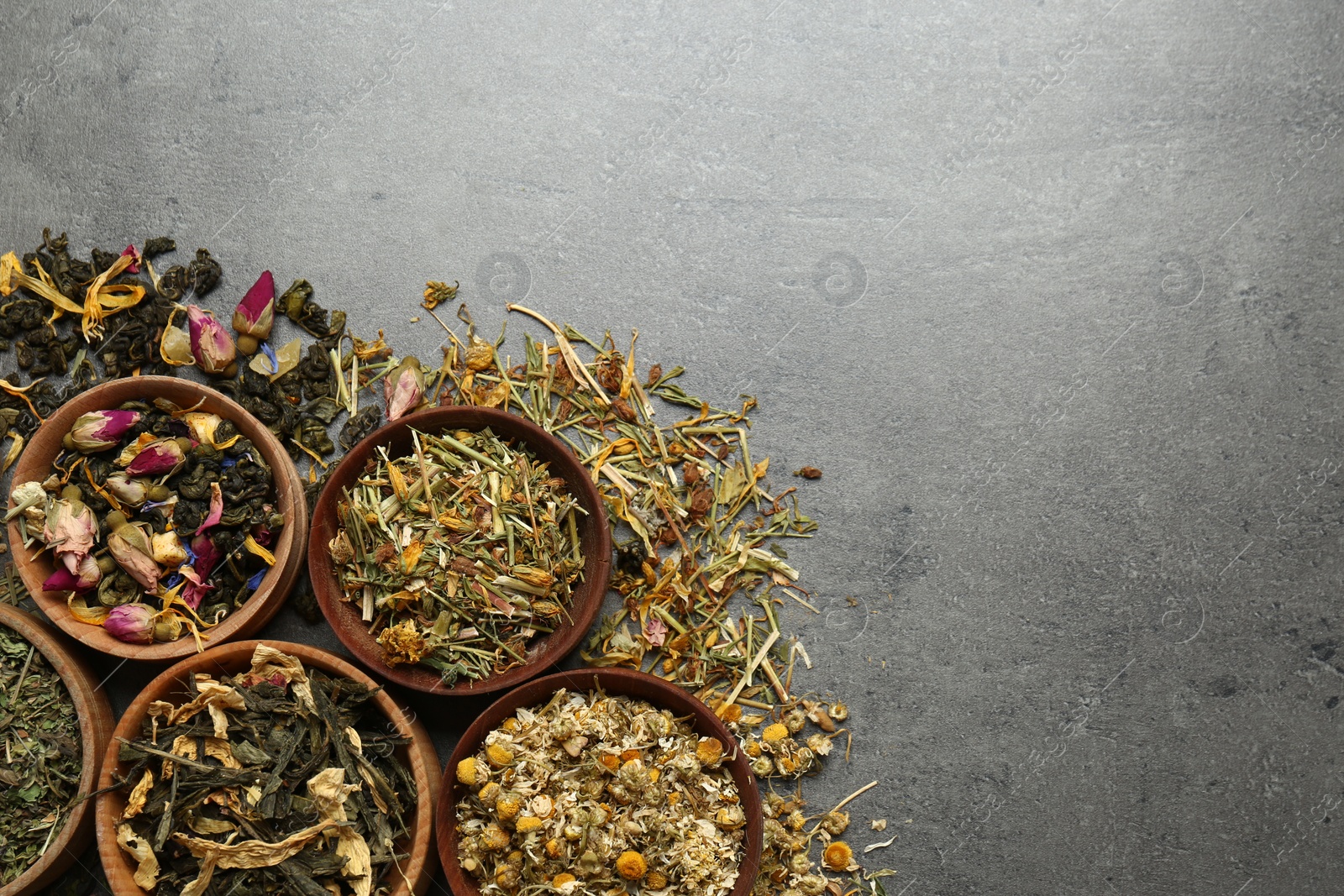 Photo of Flat lay composition with different dry teas on grey table, space for text