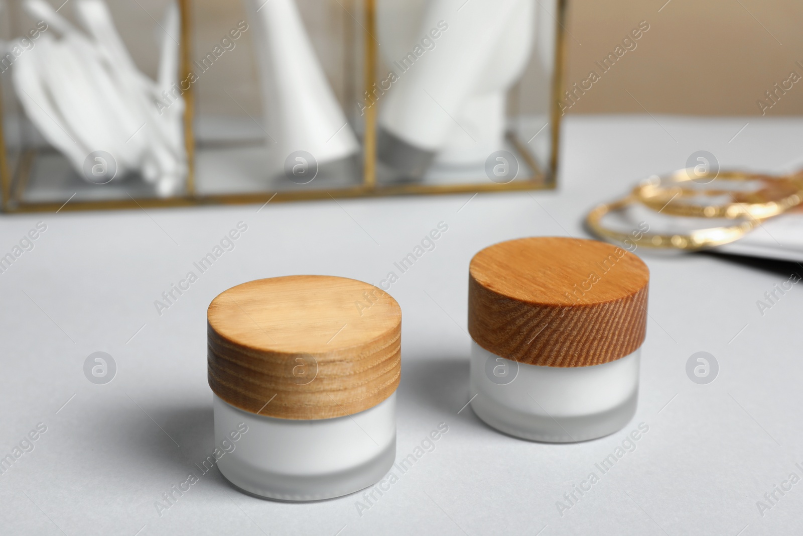 Photo of Closed jars of cream on white table