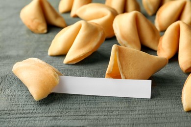 Photo of Tasty fortune cookies and paper with prediction on blue wooden table, space for text