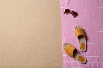 Photo of Sunglasses, shoes, blanket and space for text on beach sand, top view. Summer vacation