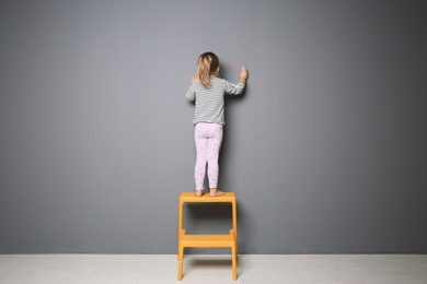 Photo of Little child drawing with colorful chalk on gray background