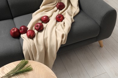 Photo of Red apples and beige blanket on grey sofa indoors, above view