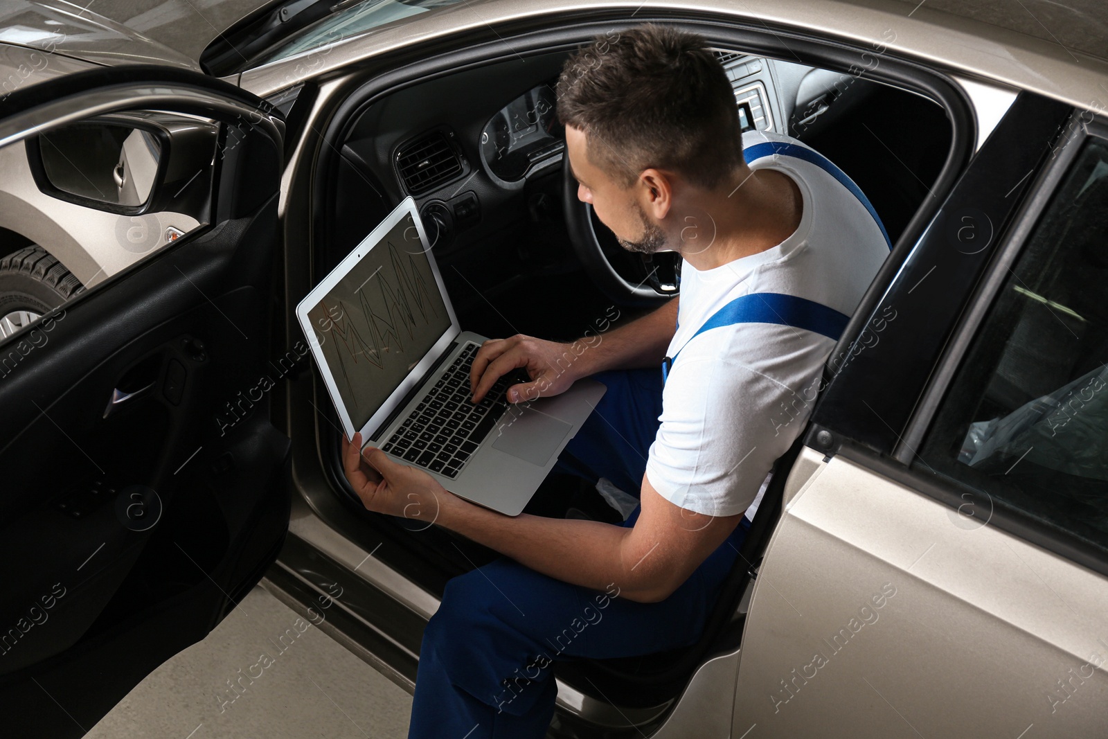 Photo of Mechanic with laptop doing car diagnostic at automobile repair shop